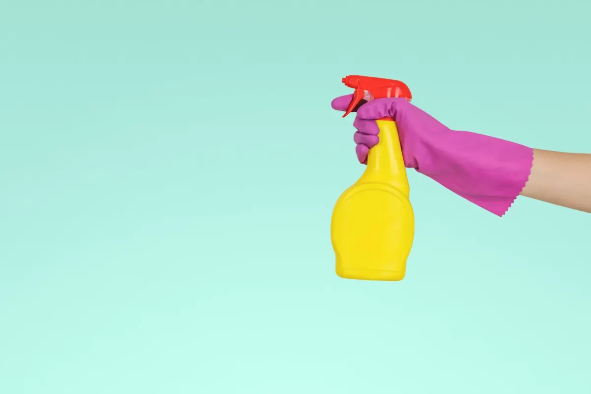 Gloved hand holding a spray bottle for a deep clean